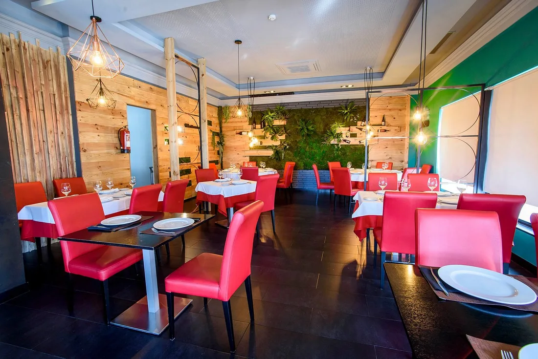 Interior de Natividad, con sillas rojas y jardín vertical